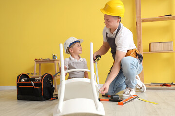 Wall Mural - Male worker with his little son assembling chair in room