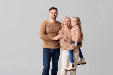 Canvas Print - Happy couple with daughter in winter clothes on grey background