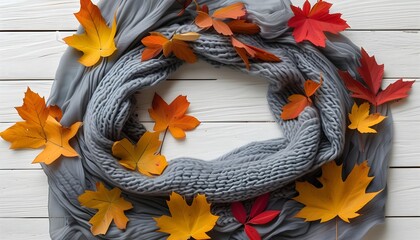 Wall Mural - Rustic autumn composition with colorful leaf frame and elegant gray scarf on white wooden background