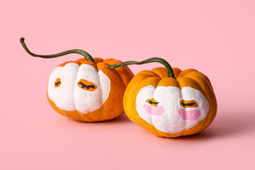 Wall Mural - Pumpkins with drawn faces and cosmetic masks on pink background