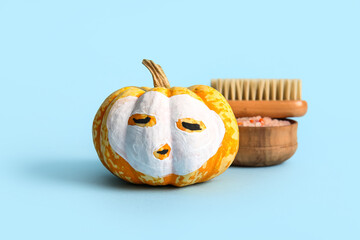 Wall Mural - Pumpkin with drawn face, cosmetic mask, sea salt and massage brush on color background