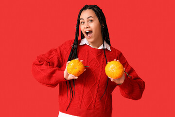 Poster - Beautiful young shocked African-American woman with pumpkins on red background