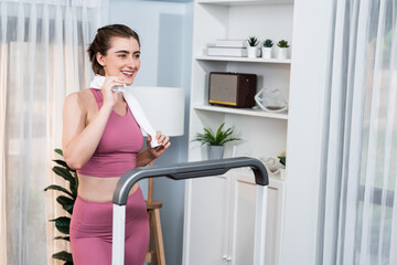 Wall Mural - Athletic and sporty woman running on treadmill running machine during home body workout exercise session for fit physique and healthy sport lifestyle at home. Gaiety home exercise workout training.