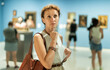 © JackF - Adult woman with brochure looking around in gallery of paintings and sculptures of museum