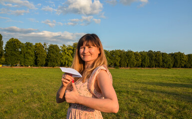 Brunette girl holding paper airplane showing thumb up. Paper airplane represents the desire to break free from constraints, explore new possibilities symbolizes creativity and the power of imagination