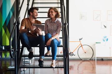 Poster - Design, tablet and talking with business people on stairs in creative workplace together for planning. Collaboration, conversation or tech with employee man and woman in office for project discussion