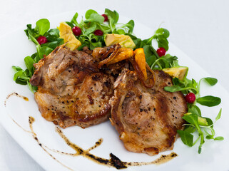 Cooked fried pork meat chops with with greens, avocado and berries at plate