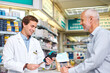 © peopleimages.com - Pharmacy, pills and payment with people in store for medicine, advice and healthcare. Medical, insurance and antibiotic prescription with pharmacist in clinic for help, drugstore and dispensary