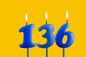 Blue birthday candle on yellow background - Number 136