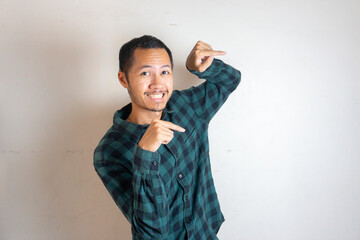 Young Adult Asian men pointing finger to the right with smiling face and exited expression with isolated white background