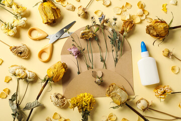 Wall Mural - Dried flowers, envelope, glue and scissors on beige background, top viewа