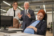 © Михаил Решетников - Elderly Caucasian man and woman giggling behind their sleeping pregnant colleague in the office.