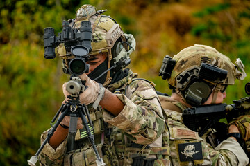 A group of military men in combat gear patrol in the middle of a desert and tropical jungle. Soldiers in full combat gear in dry weather conditions assemble and march on a mission.