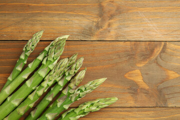 Poster - Fresh green asparagus stems on wooden table, top view. Space for text