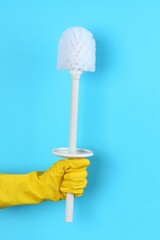 Canvas Print - Woman holding white toilet brush on light blue background, closeup. Cleaning tool