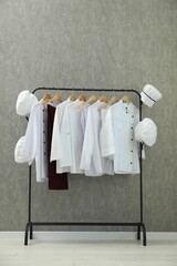 Wall Mural - Chefs' uniforms on clothing rack near grey wall indoors