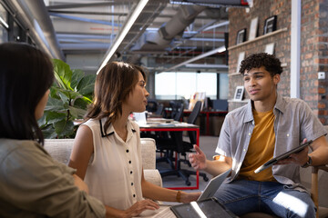 Discussing project, diverse professionals collaborating with tablet and laptop in modern office