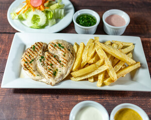 grilled chicken with french fries and fresh salad, accompanied by homemade creams.