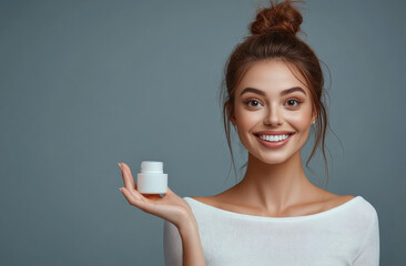 Canvas Print - A beautiful woman with brown hair in an elegant bun, smiling and looking at the camera while holding out her hand to appear cream or serum on it.