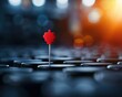 © CHONCHANOK PHOTO - A striking red map pin stands out against a blurred background of dark canisters, symbolizing guidance and direction.