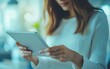 © kaiserseeing - A woman interacts with a digital tablet in a softly blurred indoor environment, representing technology, communication, and modern work practices.