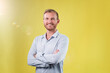 © Johnér - Portrait of handsome young businessman with crossed arms against yellow background