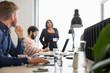 © Johnér - Female entrepreneur discussing with male colleagues sitting at desk in office