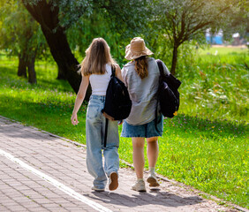 Wall Mural - Two girlfriends walk along a path in the Park
