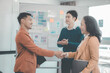 © ArLawKa - Two business people shaking hands with colleagues applauding in office atmosphere. Teamwork shaking hands with happy salespeople smiling happily when the employment contract agreement is completed.