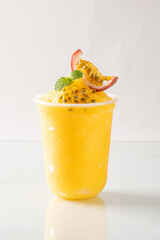refreshing chilled passion fruit drink in a plastic cup, garnished with fresh mint and passion fruit