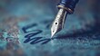 © Sri - Close-up of a fountain pen with a gold nib writing on a blue surface