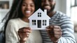 © Zaleman - Close up of a black couple holding a wooden house in the air. The concept of real estate, housing, and families