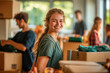 © MargoArt - Smiling young woman volunteering in a community service setting, surrounded by boxes and other volunteers working in the background