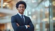 © Galib - A confident young businessman in a suit and glasses stands with his arms crossed.