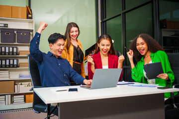 Asian colleagues, middle-aged man and young woman, happily collaborate in office workplace. They gather around laptop, discussing project management, startup plans, teamwork paper stacks on desk.