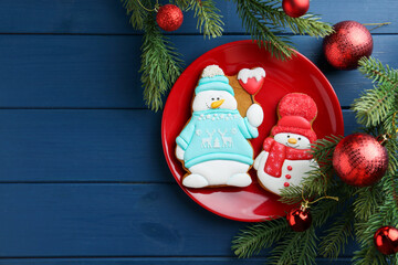 Poster - Delicious cookies in shape of snowmen and Christmas decor on blue wooden table, flat lay. Space for text