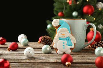 Wall Mural - Delicious cookie in shape of snowman, cup with cocoa and Christmas decor on wooden table