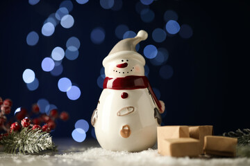 Sticker - Cute decorative snowman, fir branches and other Christmas decor on artificial snow against blurred lights