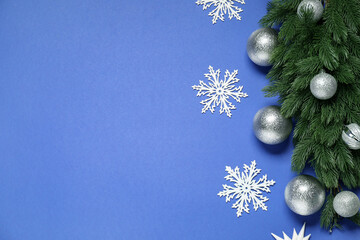 Poster - Fir tree branches, Christmas baubles and decorative snowflakes on blue background, flat lay. Space for text