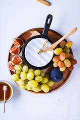 Wall Mural - Baked camembert cheese in cast iron pan with fresh figs, grapes, and honey