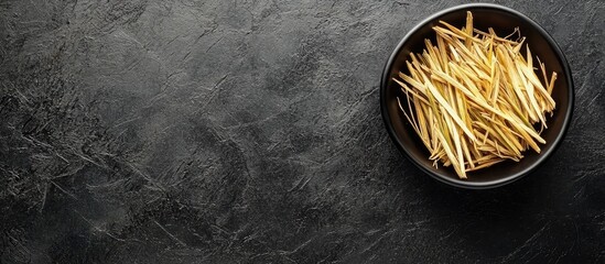 Wall Mural - Bowl of fragrant dried lemongrass on a black table top view Room for text. with copy space image. Place for adding text or design