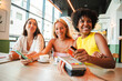 © Jose Calsina - A cheerful young African American woman is settling her bill with a contactless creditcard at a restaurant. She smiles as she hands over her credit card to complete the payment with the cashier