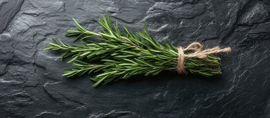 Poster - Fresh rosemary bundle and jute twine on a black stone table backdrop Cooking spices Top view banner. with copy space image. Place for adding text or design
