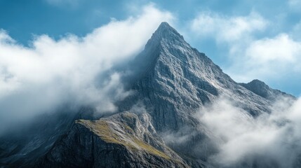 Wall Mural - Majestic mountain peak surrounded by clouds under a clear blue sky.