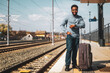 © inesbazdar - Happy man with suitcase standing on railway station.