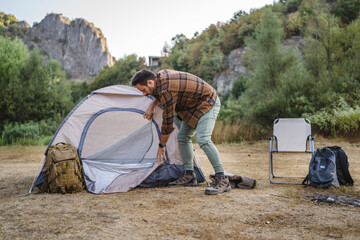 Adult man setting up a tent ready for camping trip at forest