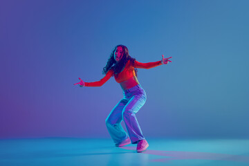 Canvas Print - Hip hop training session in full motion, female dancer performing with passion against gradient blue background in neon light. Concept of freestyle dance, modernity, urban culture, youth