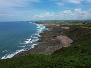 Sticker - Stunning coastal landscape with rocky shoreline and green hills.