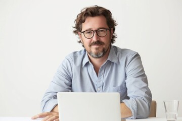 Leinwandbilder - A person sits at a table with a laptop, focused on work or study