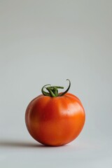 Wall Mural - A single ripe tomato sits alone on a clean white surface, perfect for food photography or illustration